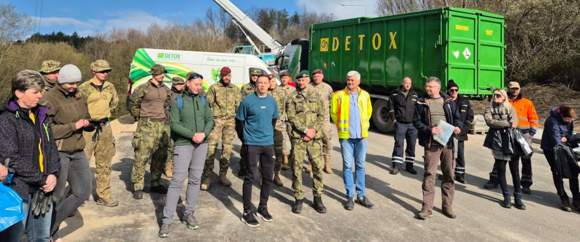 &Uacute;častn&iacute;ci čistiacej akcie stoja spolu pred vozidlami a kontajnerom spoločnosti DETOX po ukončen&iacute; zberu odpadu.
